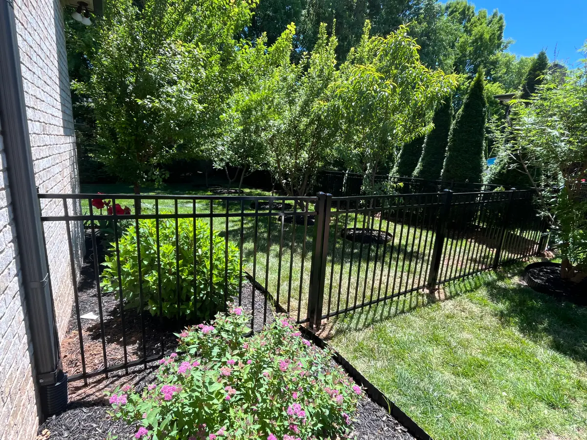 Black aluminum fence residential with flowers, installed by Duck Duck Fence