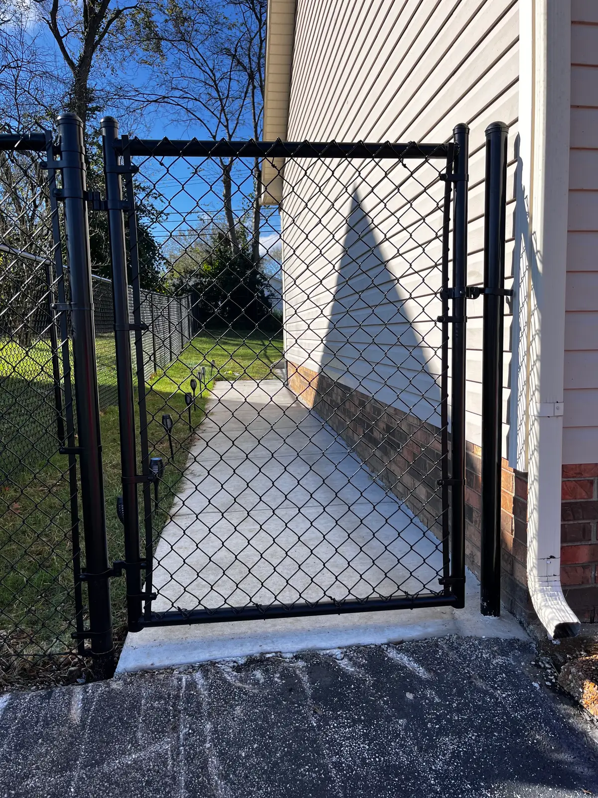 Ornamental iron driveway gate on brick columns at a country home