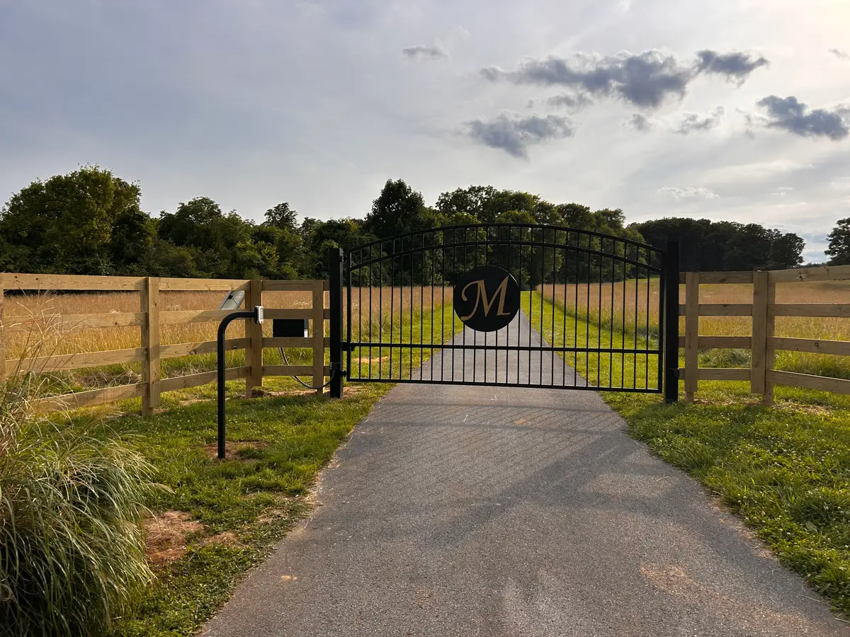 Black X-brace farm gate and board fence under a dramatic Tennessee sky