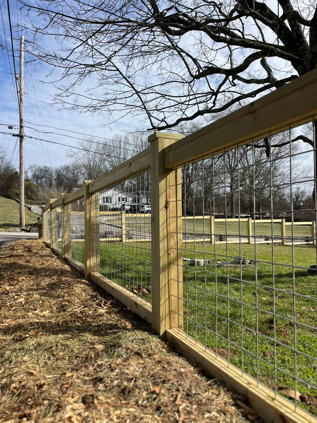 Wood-frame wire fence enclosing a rural backyard